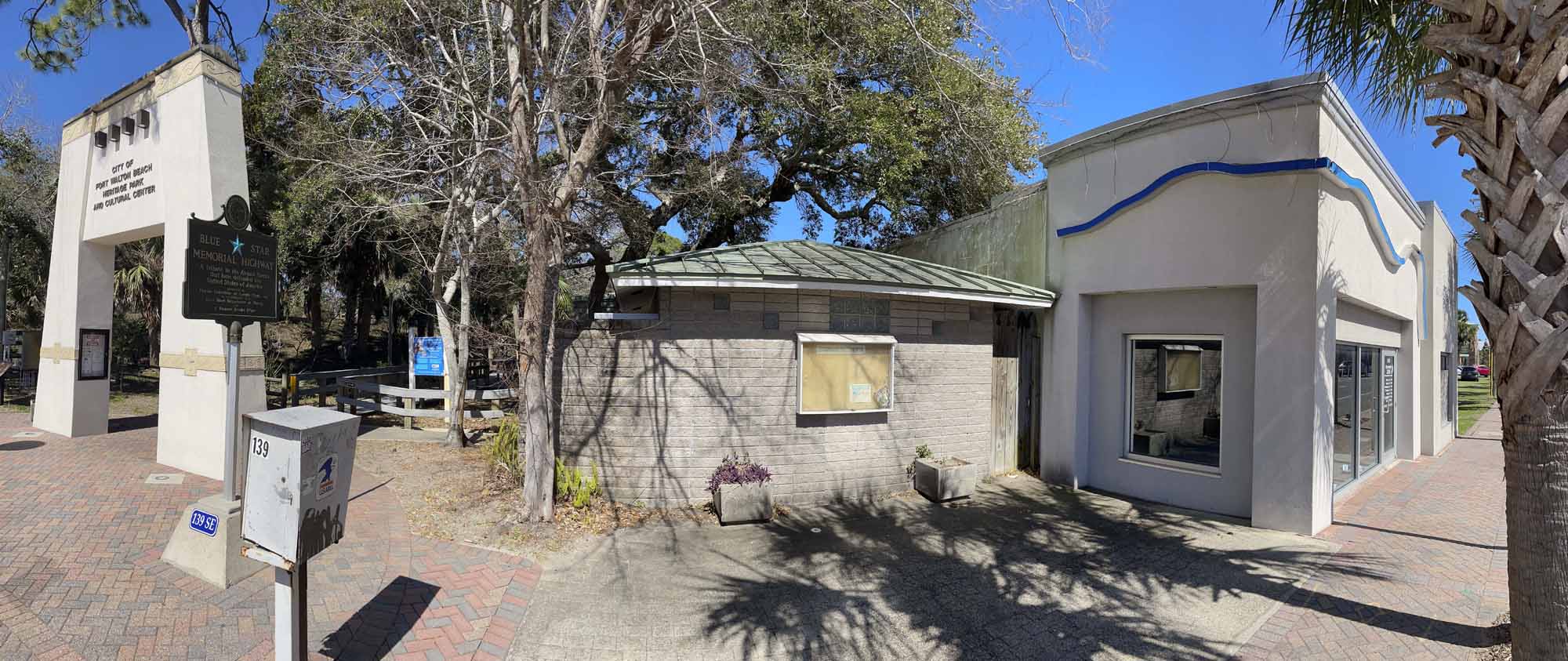 A view of the public restrooms and Bluewater Zoo buildings in front of Heritage Park and Cultural