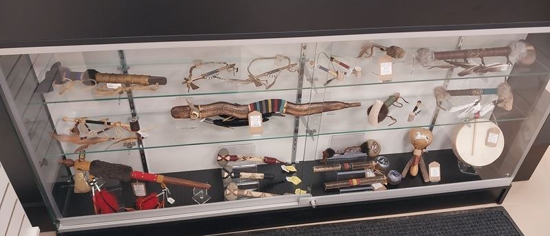 A glass display case in the new museum store containing native made items for sale